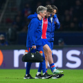 PARIS, FRANCE - OCTOBER 20: Khvicha Kvaratskhelia of Paris Saint-Germain is helped off the pitch by medical staff after sustaining an injury during the UEFA Champions League 2026/27 League Phase MD3 match between Paris Saint-Germain and FC Barcelona at Parc des Princes on October 20, 2026 in Paris, France. (Photo by Franco Arland/Getty Images)