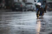 A couple with raincoat on a motorbike during hard rainfall/Dramatic scene of rainy season in Southeast Asia).Selective focus and very shallow depth of field composition