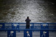 Una persona fotografía la crecida del río, en el parque lineal del Manzanares, a 20 de marzo de 2025, en Madrid (España).