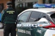 Archivo - Un agente de la Guardia Civil, de espaldas, junto a un vehículo oficial.