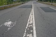Tramo de carretera con firme y marcas viales en mal estado.