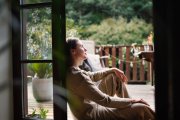 Mujer sentada junto a una ventana abierta, contemplando la naturaleza y disfrutando de un momento de serenidad personal.