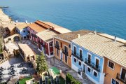 Casas pastel en fila colgando sobre el acantilado frente al Mediterráneo.