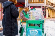 Un vendedor de lotería ofrece boletos del sorteo navideño y juegos de rasca en una céntrica calle comercial, donde muchos españoles prueban suerte cada diciembre.