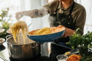 Preparación de pasta caliente en cocina doméstica con ingredientes frescos: una escena cotidiana que pone a prueba el uso de conservas como ingrediente principal.