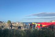 Manifestantes con una bandera gigante de España en una playa de Ceuta