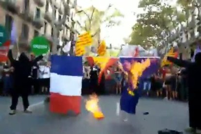 Encapuchados de la CUP (Arrán) quemando este lunes en la Diada la bandera de Francia, España y la UE.