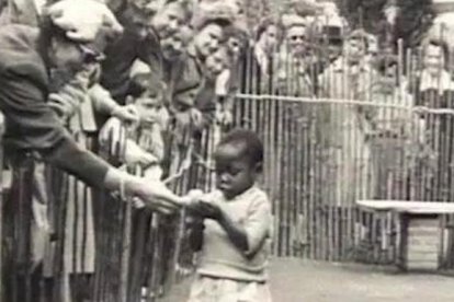 Visitantes intentando acariciar a una niña negra, en un zoo humano de Bélgica en 1958