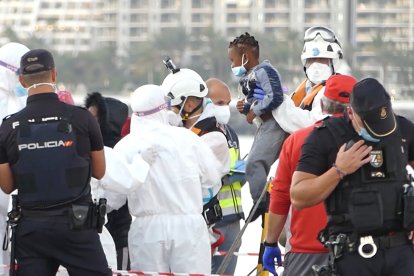 Un miembro de la Cruz Roja ayuda a bajar del barco a un niño migrante en el puerto de Arguineguín, Gran Canaria.