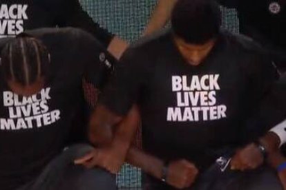 Jugadores de los Lakers escuchan, de rodillas y con camiseta de Black Lives Matter, el himno estadounidense.