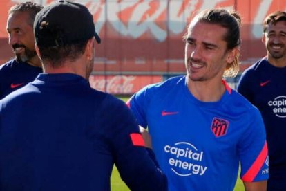 Griezmann, aún sin cortarse el pelo, saluda a Simeone en el entrenamiento de esta mañana.