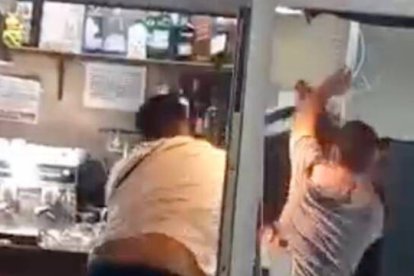 Momento en el que un hombre lanza una silla contra otras personas dentro del bar durante la pelea