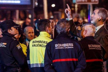 Felipe VI conversa con bomberos y miembros de los fuerzas y cuerpos de seguridad del estado mientras contempla el esqueleto del edificio calcinado en el incendio de Campanar.