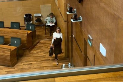 Imagen de los asientos de Vox en el pleno del Ayuntamiento de València vacíos tras abandonar sus ediles la sesión y de una de las representantes de este partido saliendo de la sala.