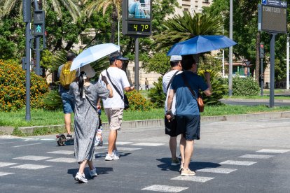 Imágenes de personas al lado de un termómetro en las calles de Sevilla en julio.