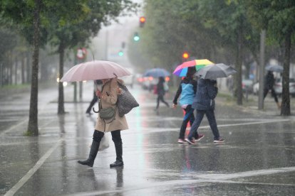 Varias personas caminan bajo la lluvia,.