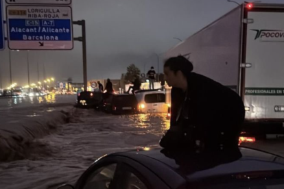 Una mujer se sube al techo de su coche en la autovía inundada para evitar que el agua la alcance