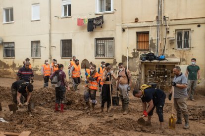 Voluntarios y vecinos retiran barro con palas, en el barrio de El Raval, en Algemesí.