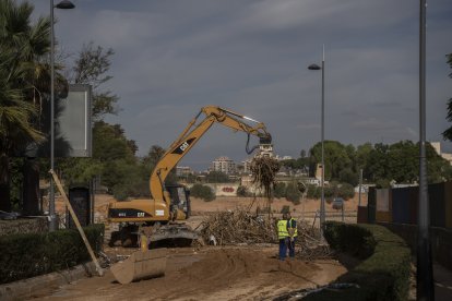 Una máquina excavadora realiza tareas de limpieza en Torrent tras el paso de la DANA