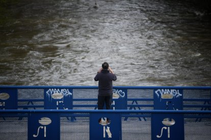 Una persona fotografía la crecida del río, en el parque lineal del Manzanares, a 20 de marzo de 2025, en Madrid (España).