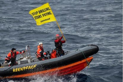 Activistas de Greenpeace en una lancha motora lanzan el mensaje 'Dejen de perforar, empiecen a pagar'.
