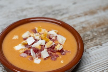 Plato de barro con salmorejo cordobés, cubierto con huevo duro y jamón curado.