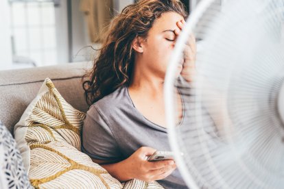 Mujer agotada por el calor frente a un ventilador durante una ola de calor