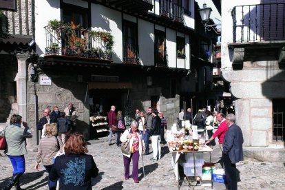 Plaza del casco histórico de La Alberca con puestos artesanales y turistas paseando entre casas tradicionales de piedra y madera.