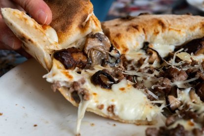 Pizza blanca trufada recién sacada del horno, con queso fundido y champiñones