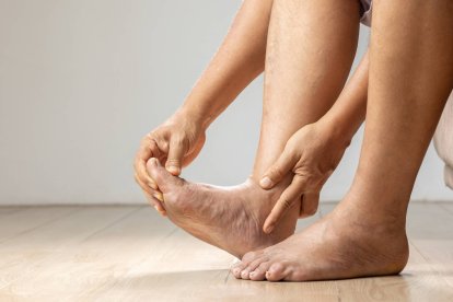 Persona masajeando sus pies hinchados, mostrando signos de inflamación por retención de líquidos.