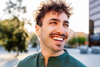 Hombre adulto sonriente disfrutando de un momento de felicidad al aire libre en la ciudad.