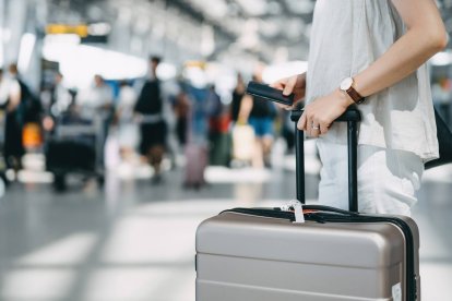 Una pasajera en el aeropuerto con su equipaje de mano, en plena temporada alta de verano, marcada por cancelaciones y huelgas en aerolíneas como Ryanair.