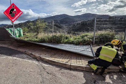 Efectivos de los bomberos, retirando una valla caída sobre una carretera.
