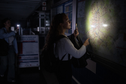 Una mujer ilumina con la linterna del móvil un plano de la red de Metro de Madrid en una estación.
Alejandro Martínez Vélez / Europa Press
28/4/2025