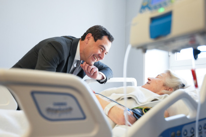 Juanma Moreno con una paciente ingresada en un hospital de Sevilla este lunes.