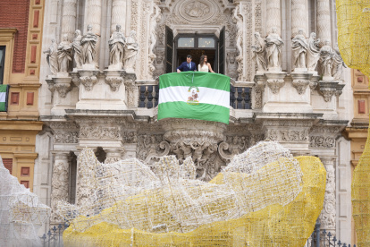 El presidente de la Junta de Andalucía, Juanma Moreno, despliega la bandera andaluza en el balcón principal de San Telmo, junto a la periodista Isabel Jiménez.