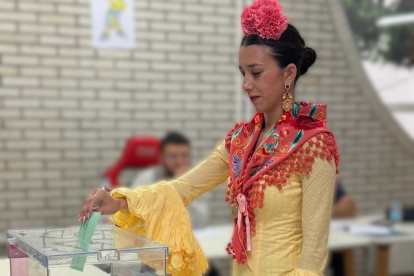 Una joven vestida de flamenca acude a votar este 17M en Andalucía.