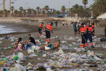 Operarios del servicio de limpieza municipal de Málaga trabajan en la retirada de basura en la playa de La Malagueta tras la celebración de la noche de San Juan.