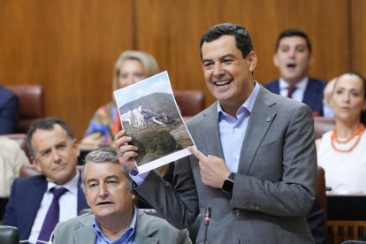 El presidente de la Junta de Andalucía, Juanma Moreno, enseña la foto del Algarrobico en pie.
