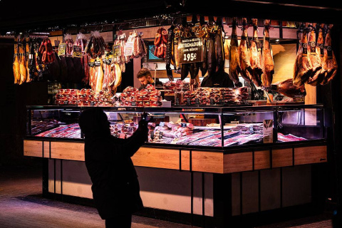 Jamones ibéricos colgados y embutidos artesanales en uno de los puestos más icónicos del Mercado de la Boquería.