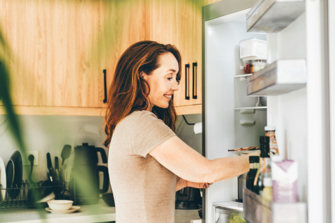 Una mujer coge alimentos del frigorífico