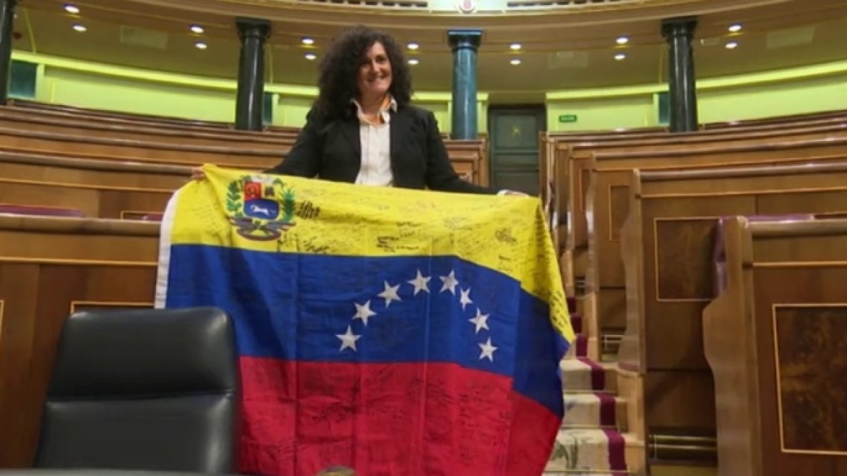 Una opositora venezolana al colocar este jueves una bandera de su país en el escaño de Pablo Iglesias.