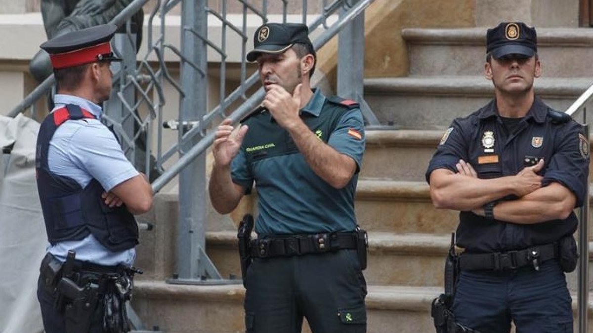 Un mosso, un guardia civil y un policía nacional, este martes frente a la Delegación del Gobierno en Barcelona.