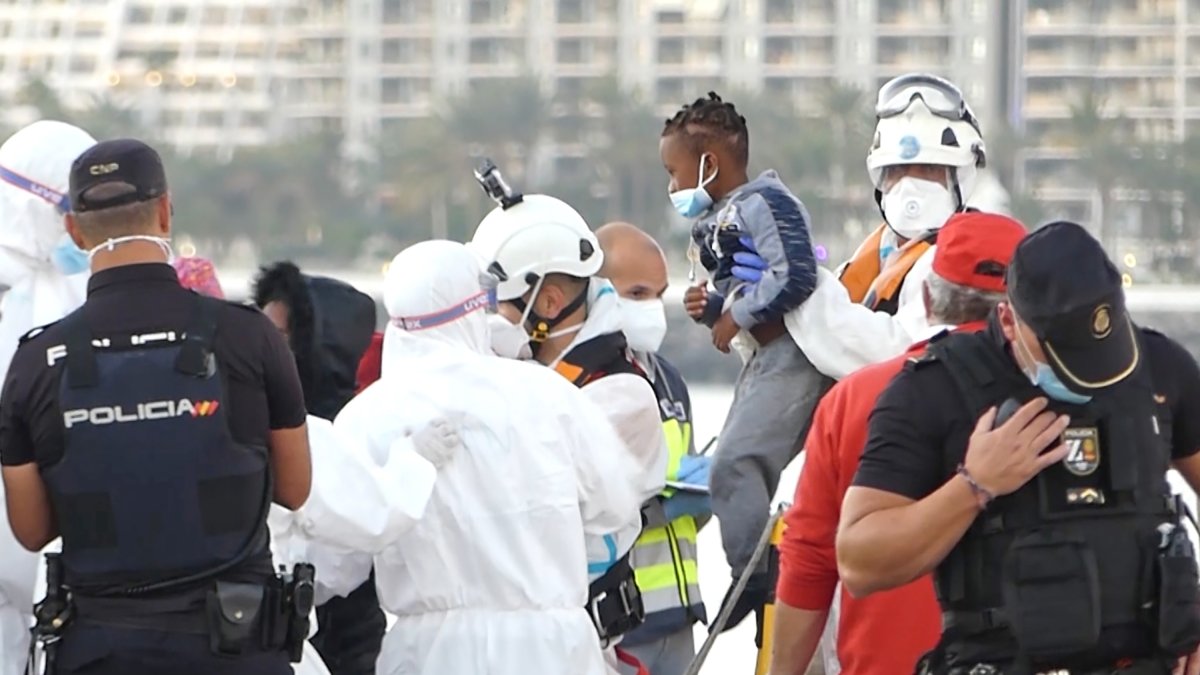 Un miembro de la Cruz Roja ayuda a bajar del barco a un niño migrante en el puerto de Arguineguín, Gran Canaria.