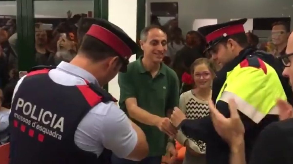 Dos mossos reciben una rosa en un colegio electoral que debían clausurar.