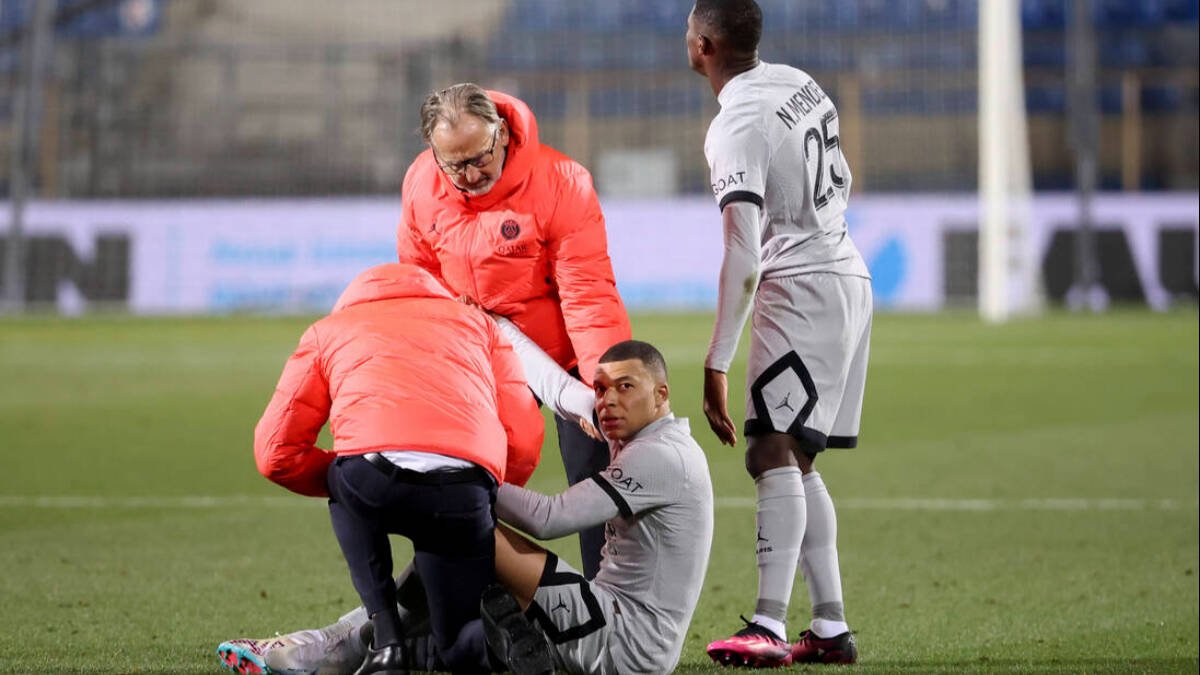 Mbappé, ayudado por los servicios médicos del PSG tras caer lesionado.