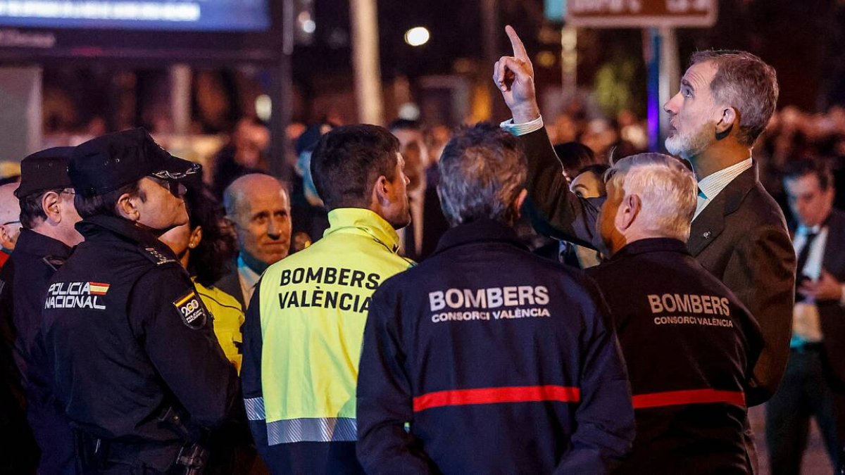 Felipe VI conversa con bomberos y miembros de los fuerzas y cuerpos de seguridad del estado mientras contempla el esqueleto del edificio calcinado en el incendio de Campanar.