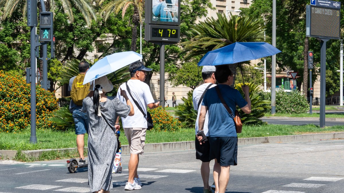 Imágenes de personas al lado de un termómetro en las calles de Sevilla en julio.