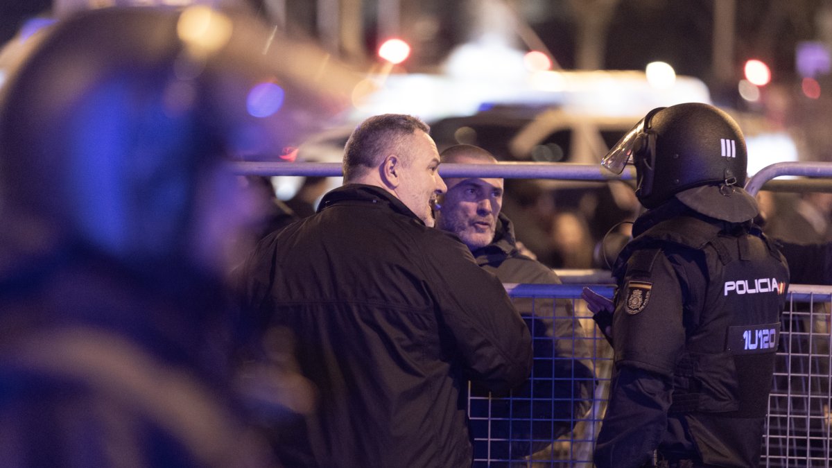 Un policía nacional habla con el líder de Desokupa, Daniel Esteve, durante una manifestación.