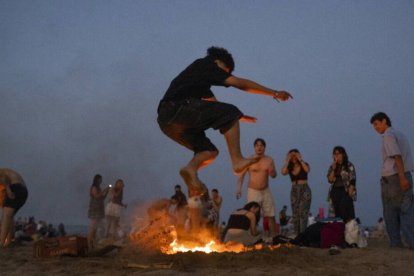 Una persona salta una hoguera durante la noche de San Juan, en la playa de la Malvarrosa / Jorge Gil.